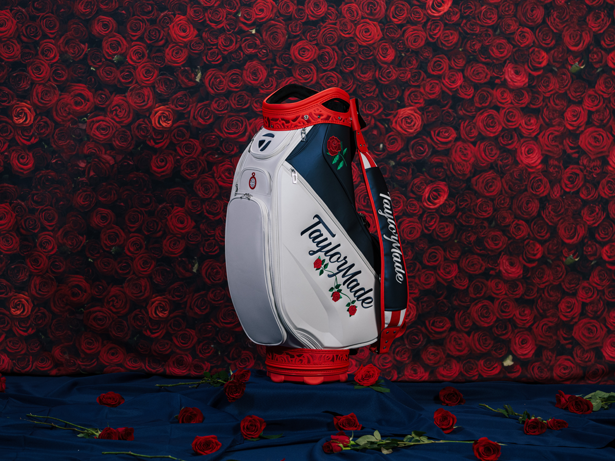 Red roses in the background, with the Women's Summer Commemorative staff bag standing on top of a navy blue blanket with red roses scattered around.