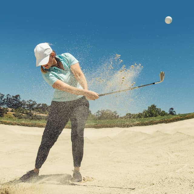 woman golfer hitting a ball out of a sand trap