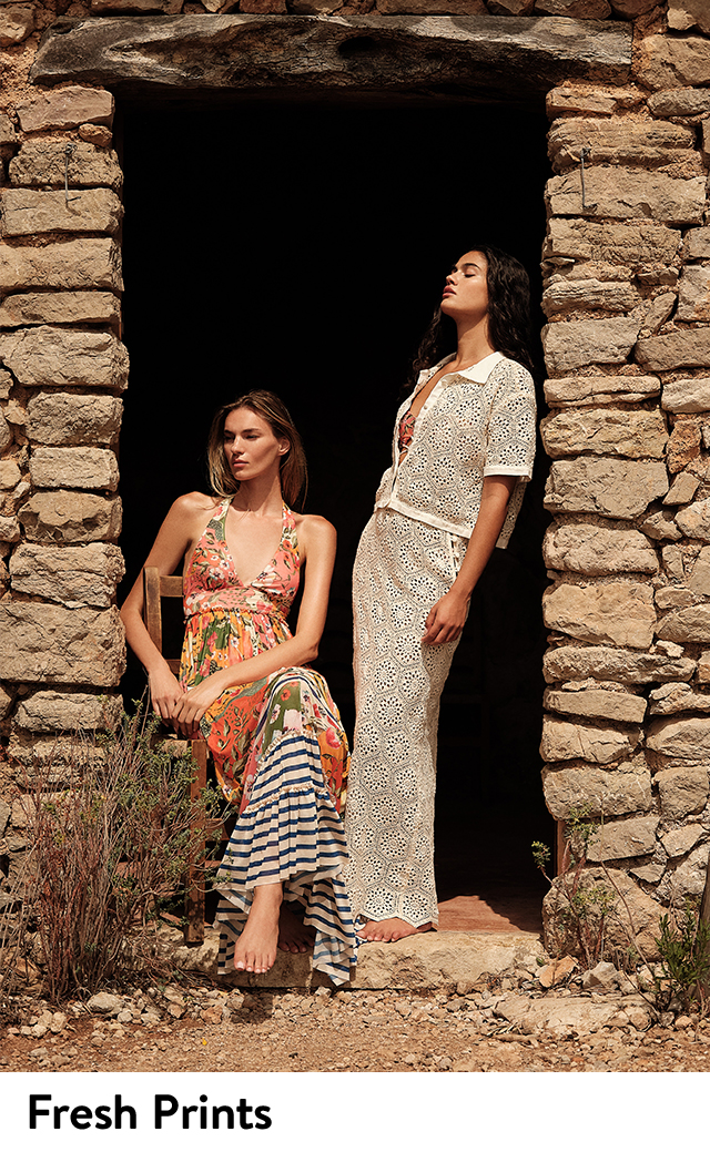 Two women wearing printed vacation outfits. 