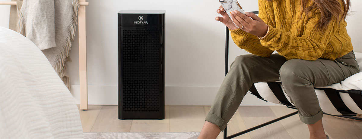 Woman on phone next to a black MA-40 air purifier