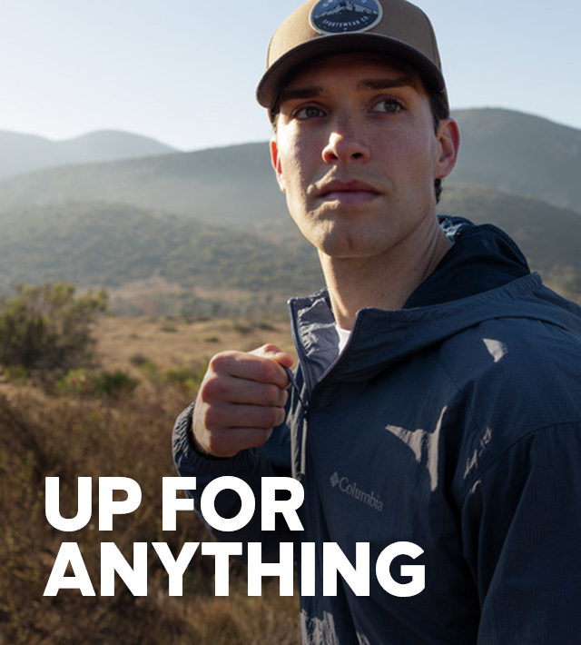 A man zipping up his jacket on a sunny hike. Up For Anything.