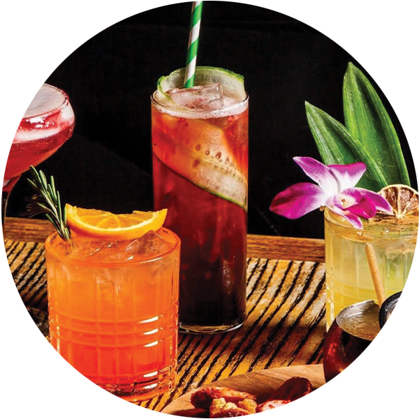 A display of four tropical cocktails garnished with fruit and flowers