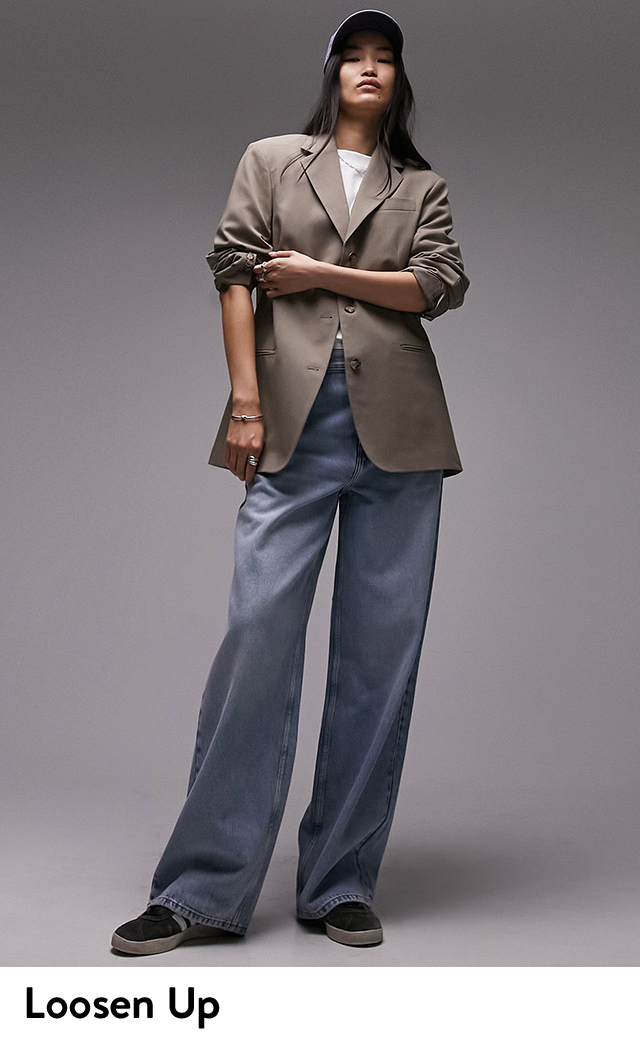 A woman wearing an oversized tan blazer, white shirt and wide-leg jeans.  