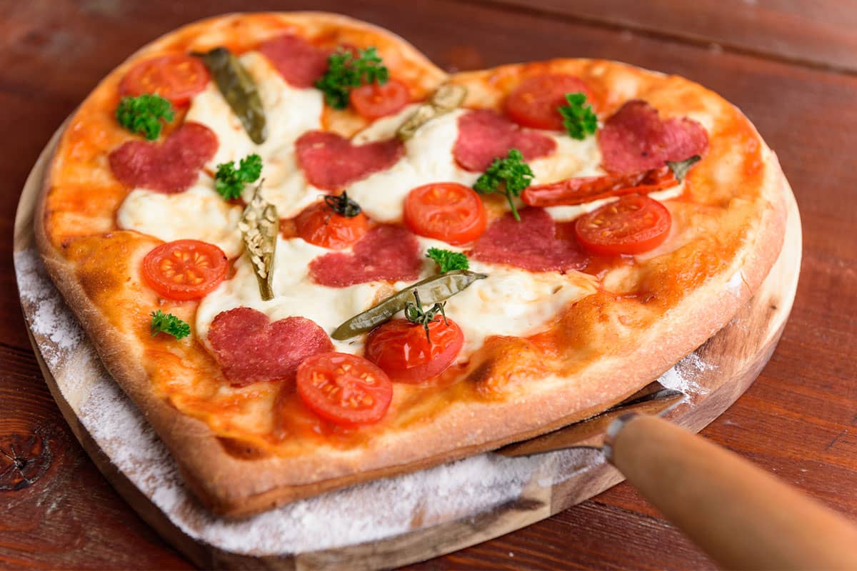 heart shaped pizza on a pizza stone