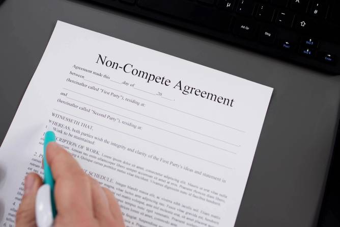 A hand signing a noncompete agreement