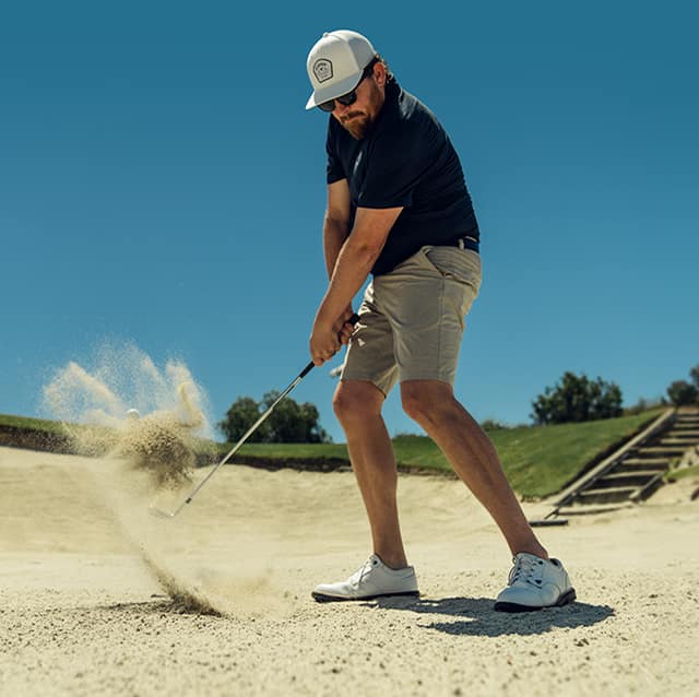 golfer hitting a wedge shot out of a bunker