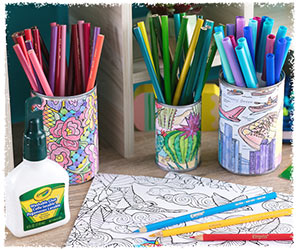 Colored-in coloring pages wrapped around tin cans with multicolor pencils and markers sitting in them