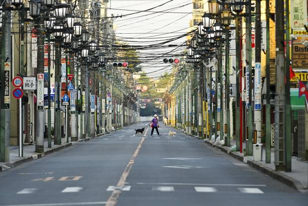  A woman walks her dogs very early in the morning on the street before the heat of the day sets in on June 14, 2024 in Tokyo, Japan