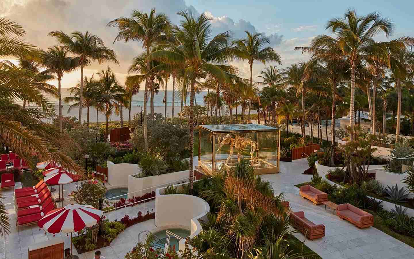 An outside patio with palm trees and furniture on the beach at the Faena Hotel