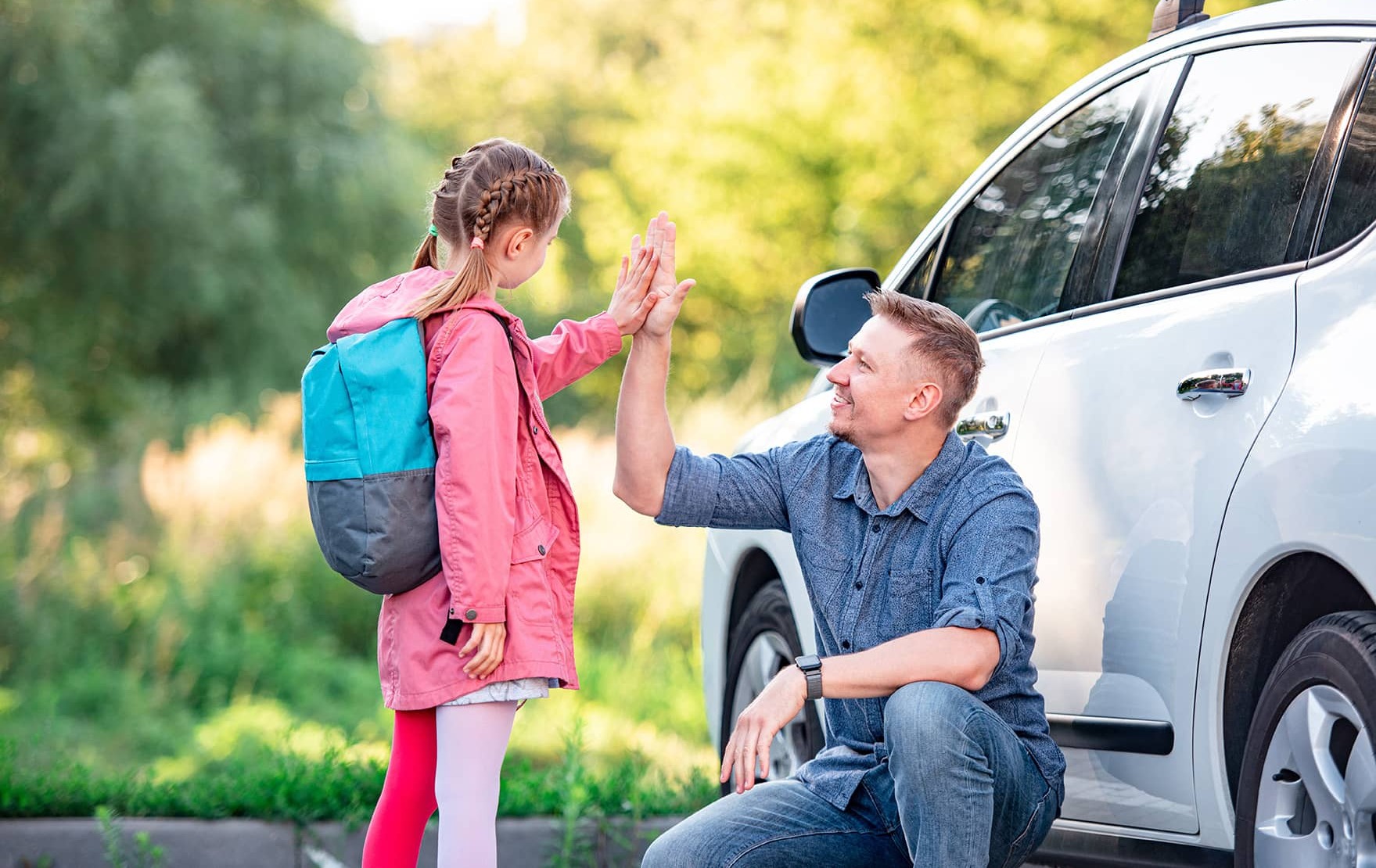 man high-fiving girl near car