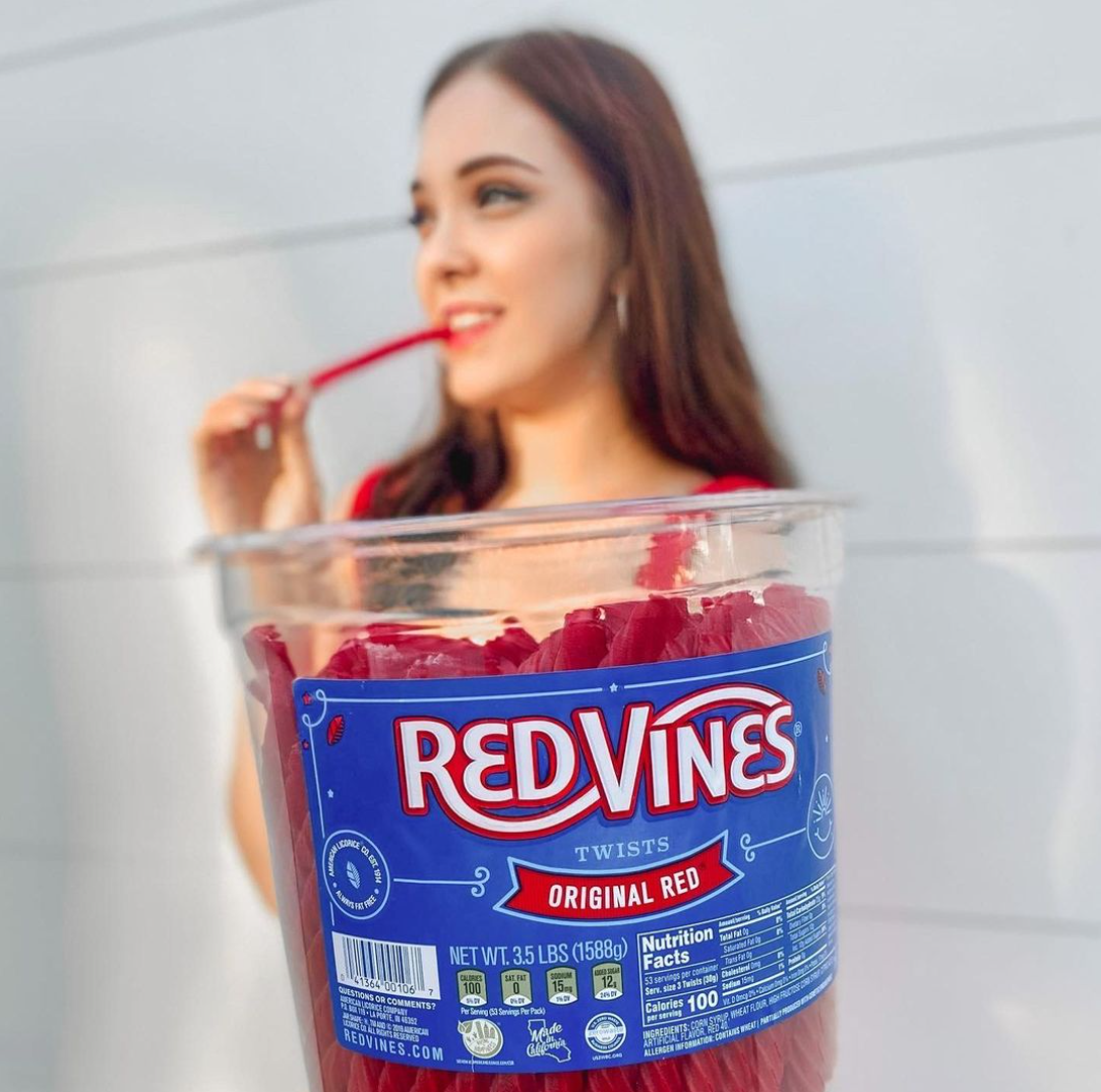 Woman smiling while holding a jar of RED VINES Original Red Twists