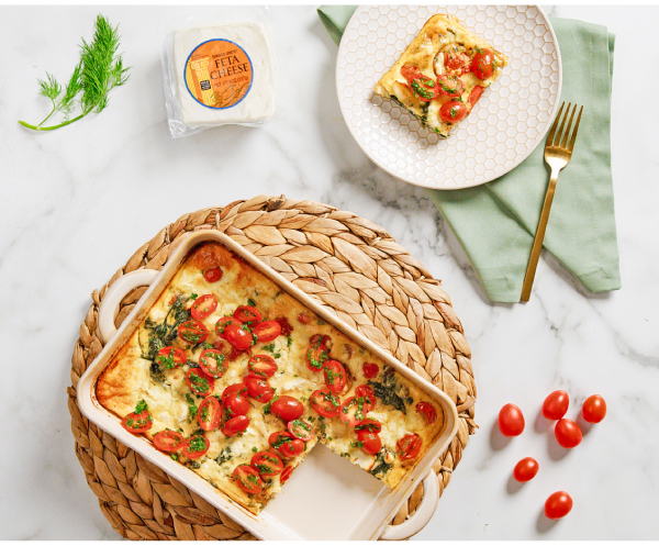 video still of a marble surface with a feta frittata in a casserole pan; one piece cut out and on a plate; Trader Joe's Feta package and a few grape tomatoes surrounding