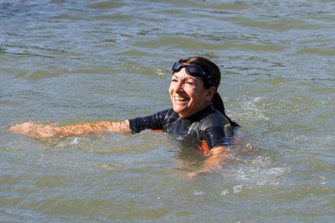 Paris Mayor Anne Hidalgo smiling while wading in Seine river in Paris.