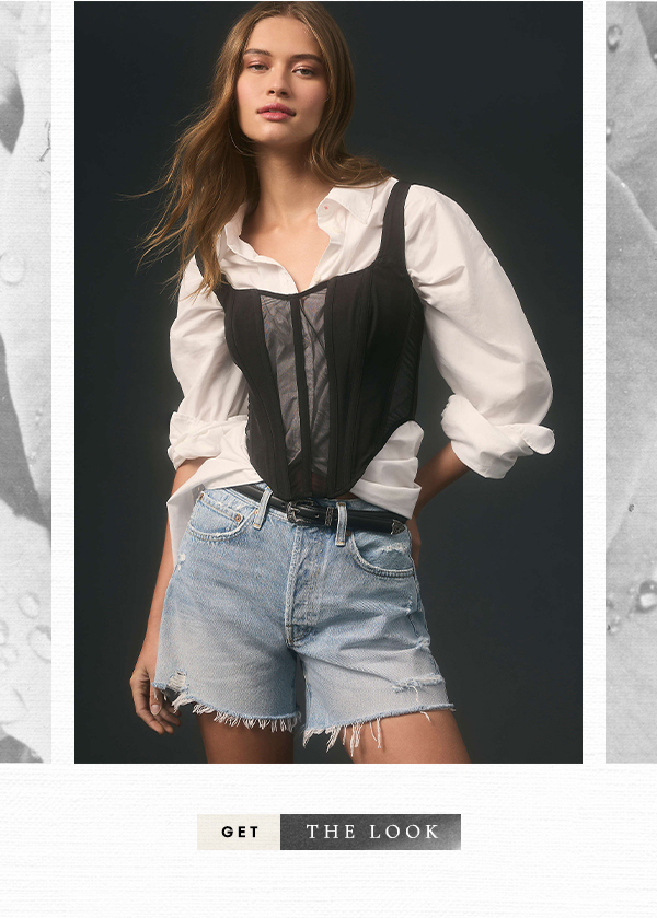 Woman wearing jeans and black corset over white buttondown. Get the look.