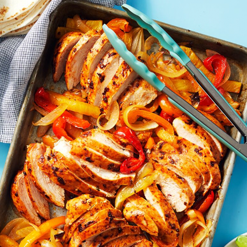 Sheet Pan Chicken Fajitas with tongs resting on the pan