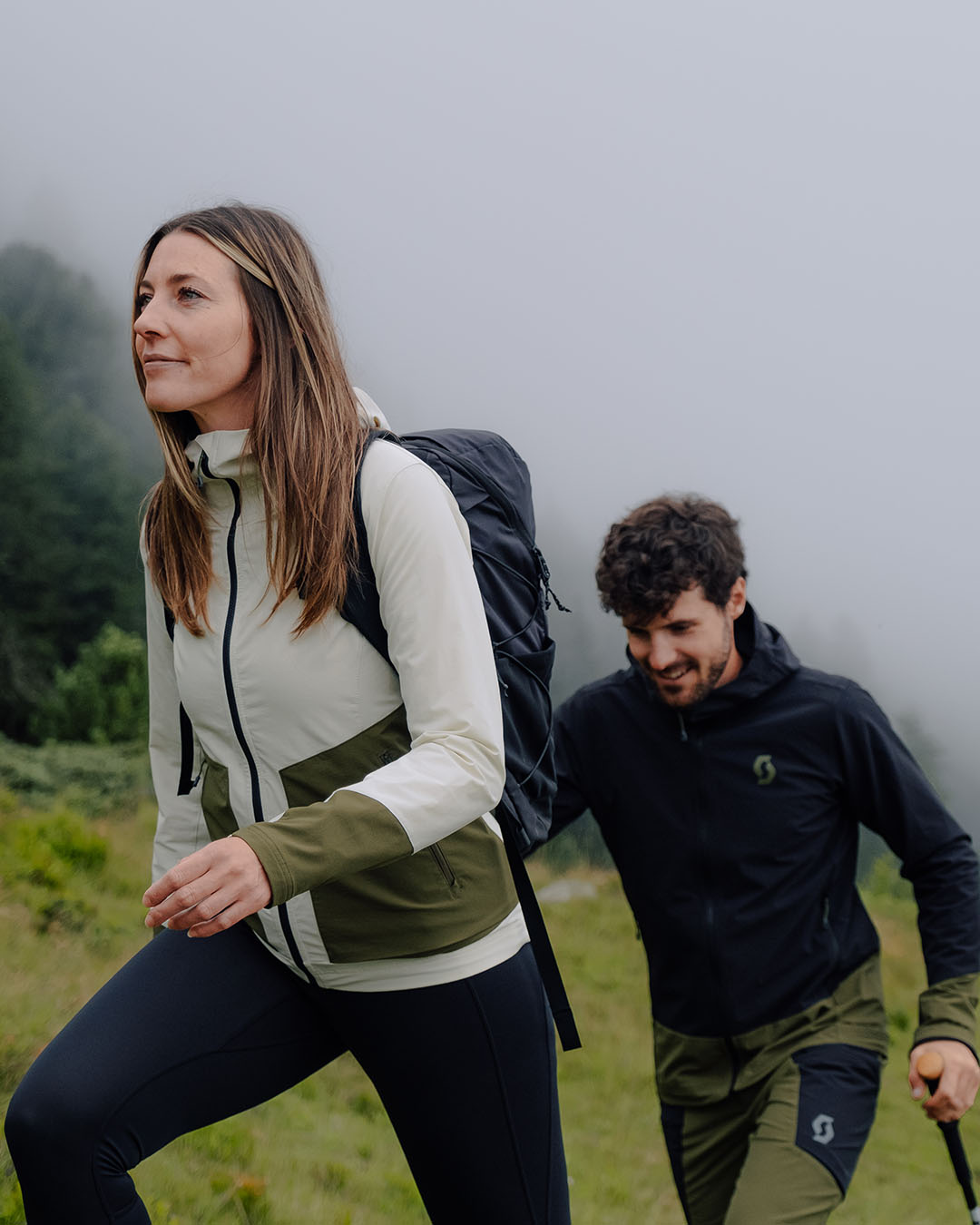 A woman and a man hiking in the mountains with their SCOTT Mountain Wear Collection gear