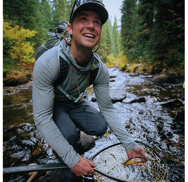 Man holding a fish while wearing the Men's PFG Uncharted™ Hoodie