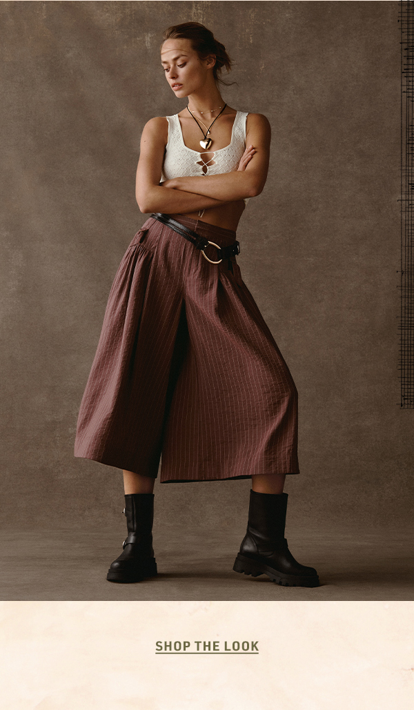 Woman in brown pinstripe skirt, white tank, and boots. Shop the look.