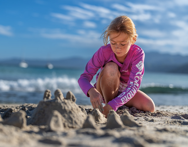 Kid playing in the sand near some water