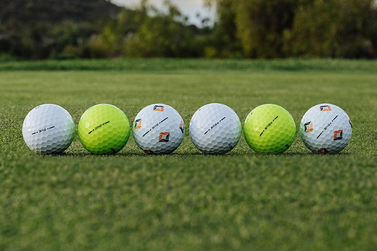 All-New TP5 white, yellow and pix and TP5x white, yellow and pix golf balls lined up on the green outdoors with trees in the background