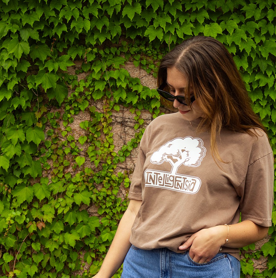 long sleeve tee with a illustration of a window, coffee plant, and text illuminating coffee in the sunlight of the window