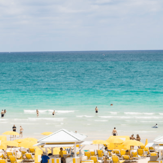 View of the ocean from the beach with yellow chairs and umbrellas