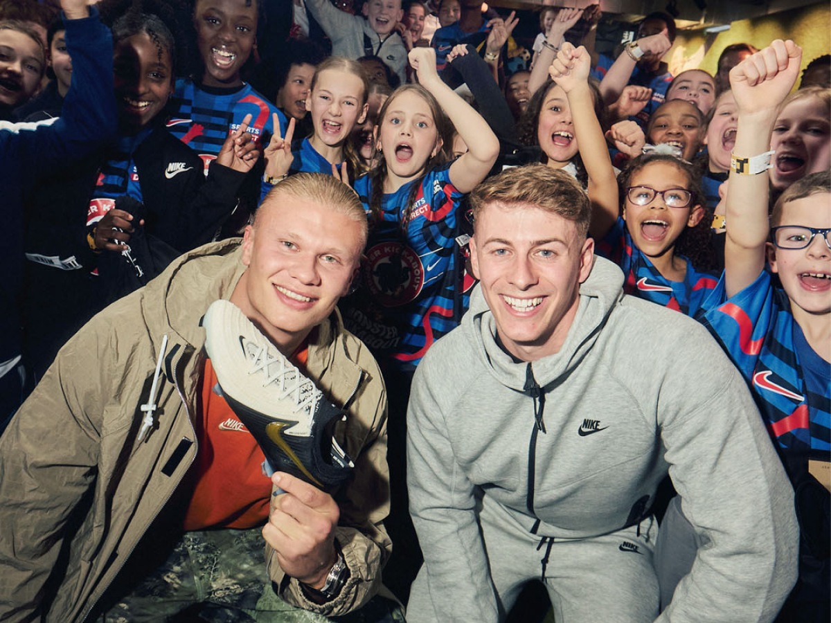 Haaland visiting Sports Direct Manchester holding the Nike Phantom GX in front of a group of Children.