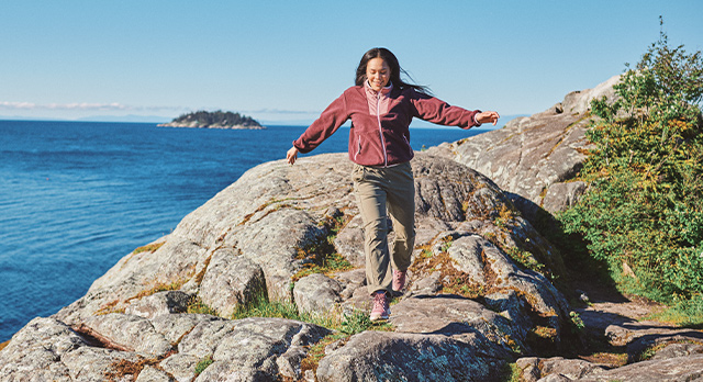 Woman jumping on a rock near the ocean