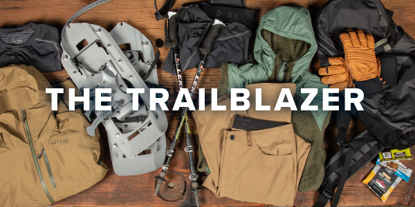 A lay down image of Beyond Clothing products that an individual who is a moderately advanced  outdoorsman. Products include snowshoes, trekking poles, hiking pants, jackets, gloves and a backpack. Text overlay saying "The Trailblazer:.