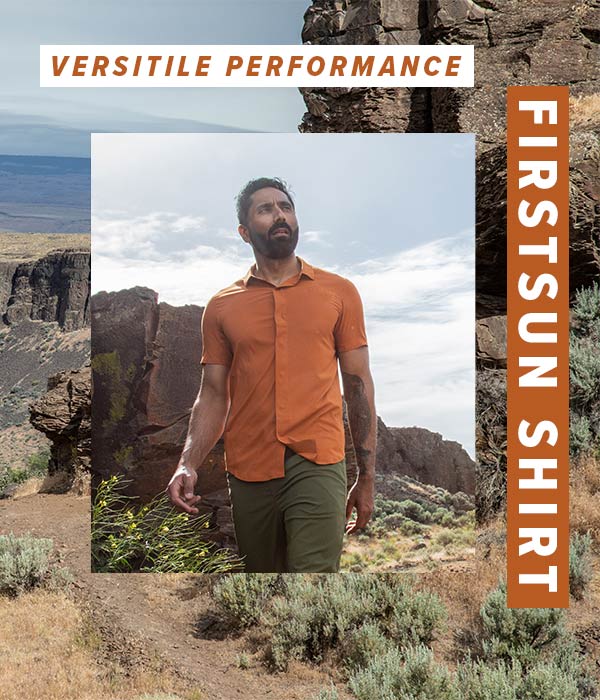 Man wearing the Desert Clay colored FirstSun Short Sleeve shirt while walking through a mountainous landscape