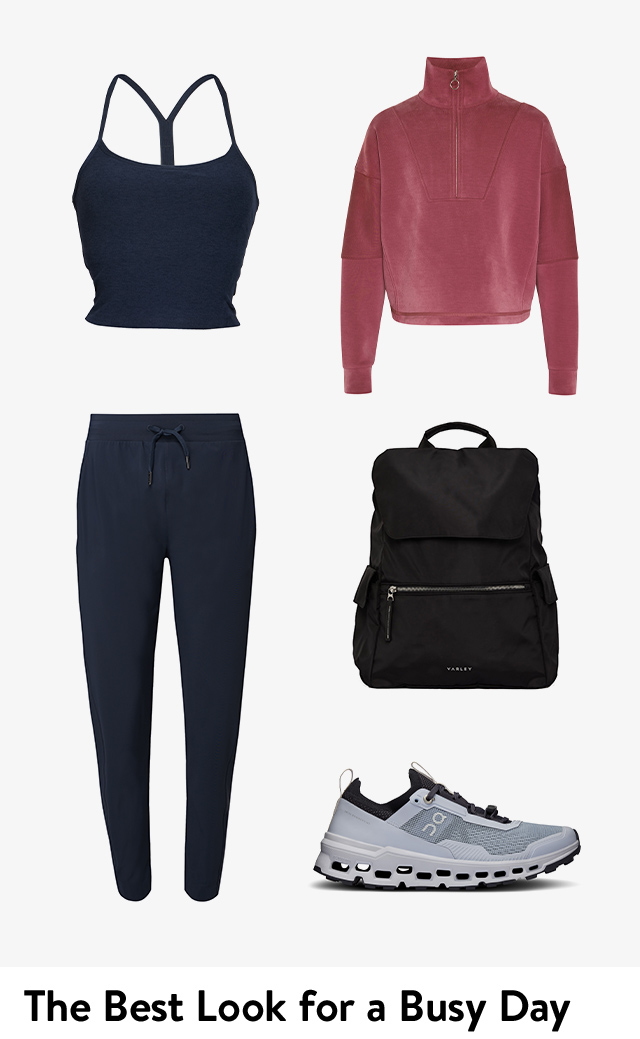 A red pullover, cropped navy tank top, casual navy pants, black backpack and grey On running sneakers.