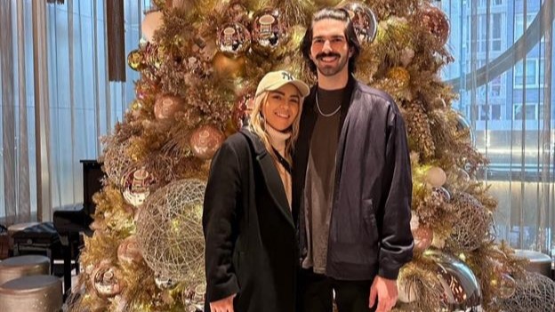 Two Delta customers pose in front of a Christmas tree.