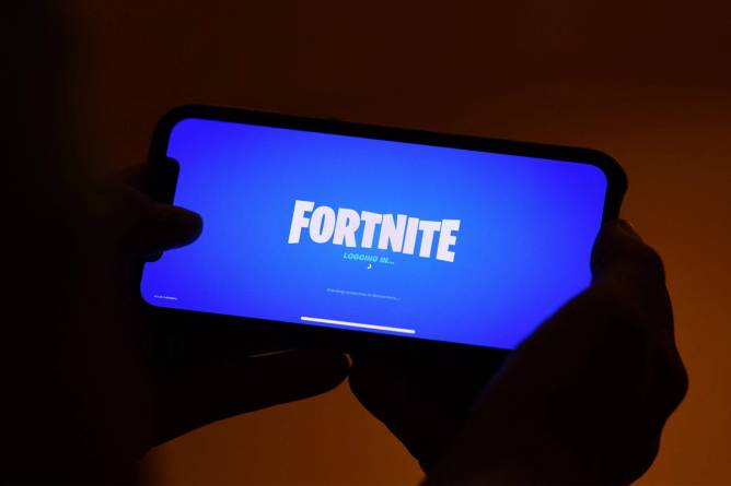 Fortnite logo on phone screen in user’s hands.