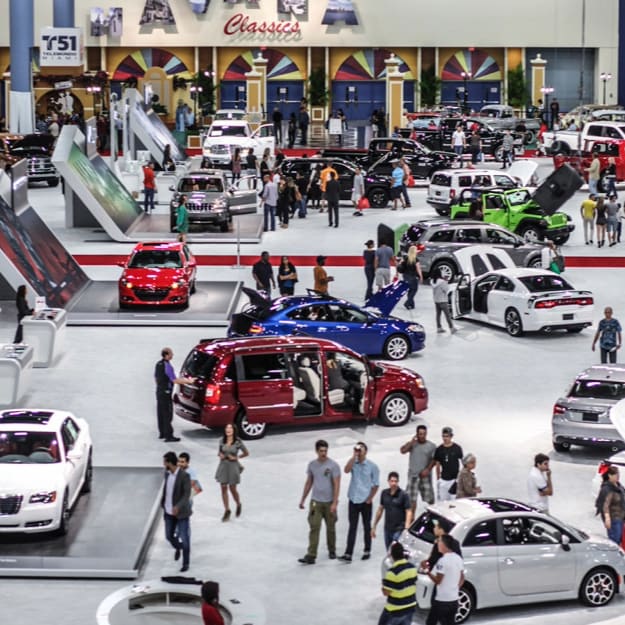 Multiple cars are displayed on an auto show exhibit floor