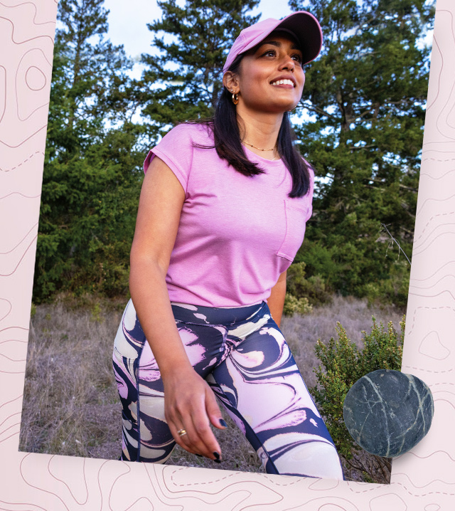 A woman in modern hiking gear smiling in a Redwood forest.