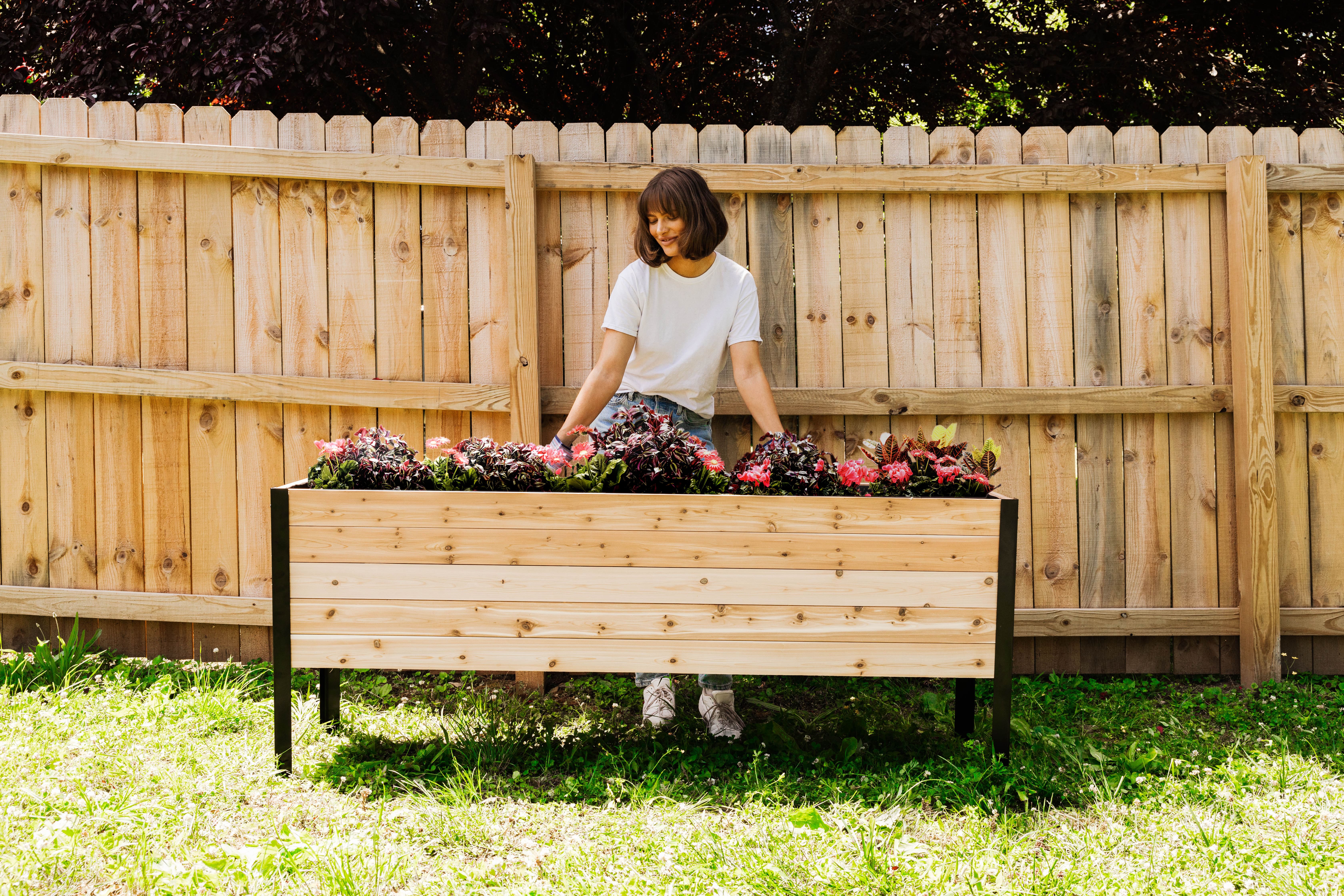 Woman planting flowers in a Cedar Planters Raised Garden Bed