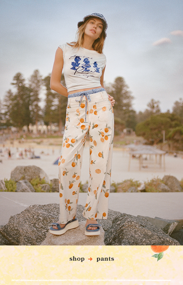 Woman wearing orange-patterned pants. Shop pants.