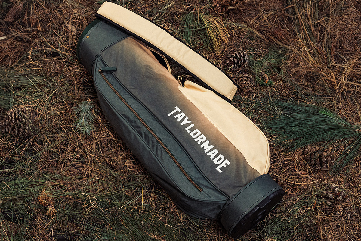 Men's Summer Commemorative Short Course Carry bag laying on top of twigs in the woods