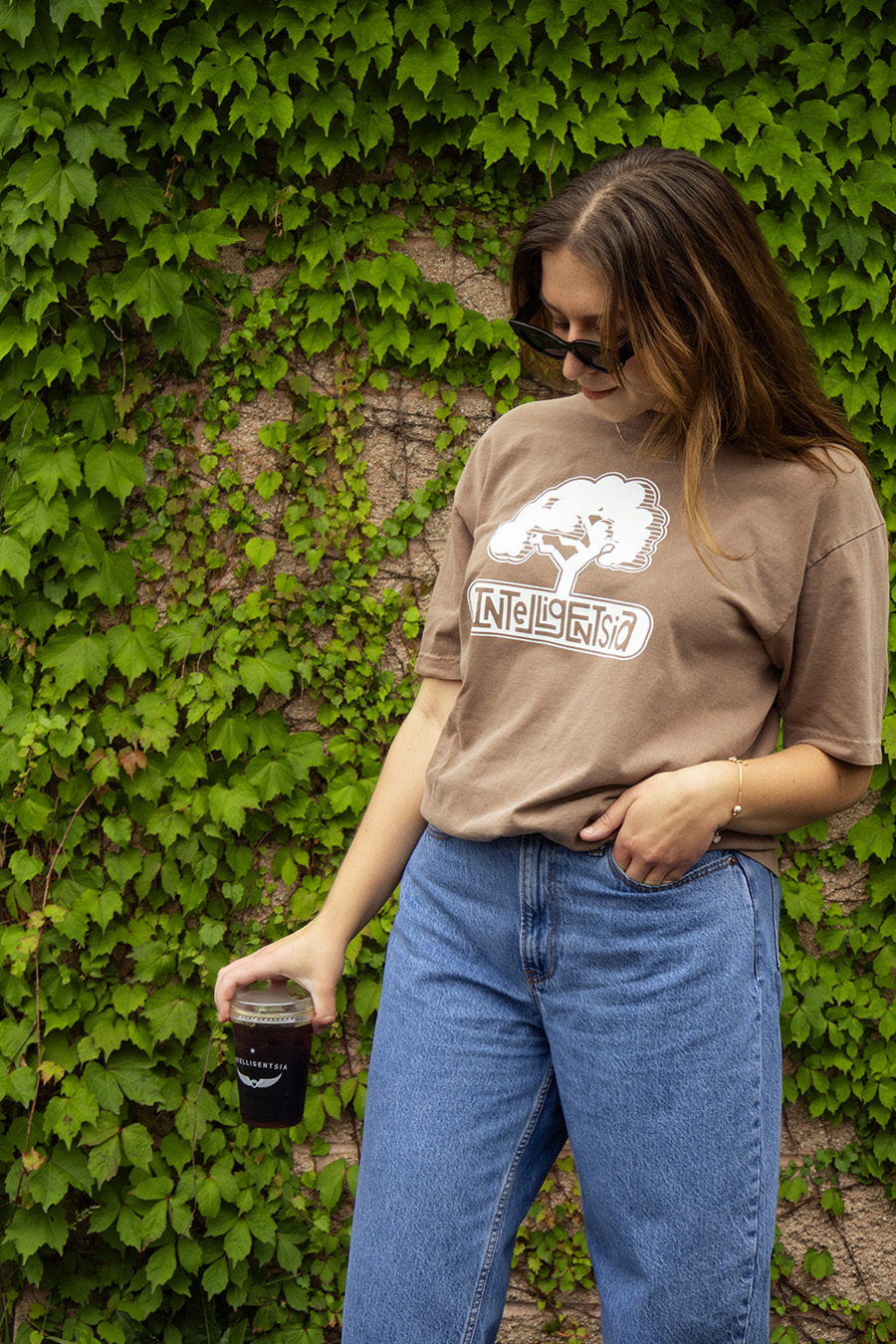 long sleeve tee with a illustration of a window, coffee plant, and text illuminating coffee in the sunlight of the window