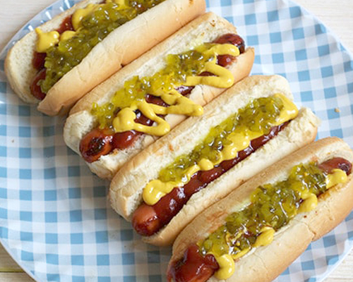 Blog idea: marinated hot dog recipe showing 4 hot dogs on a gingham plate