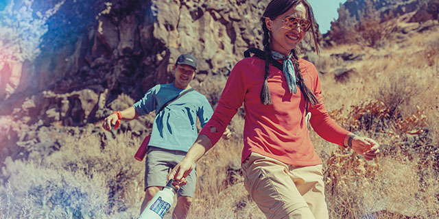 A couple hiking around boulders.