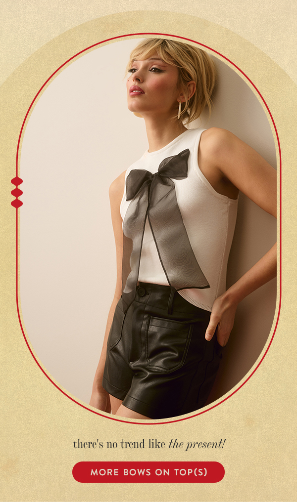 Woman in black leather short and white top with bow detail. More bows on top(s)