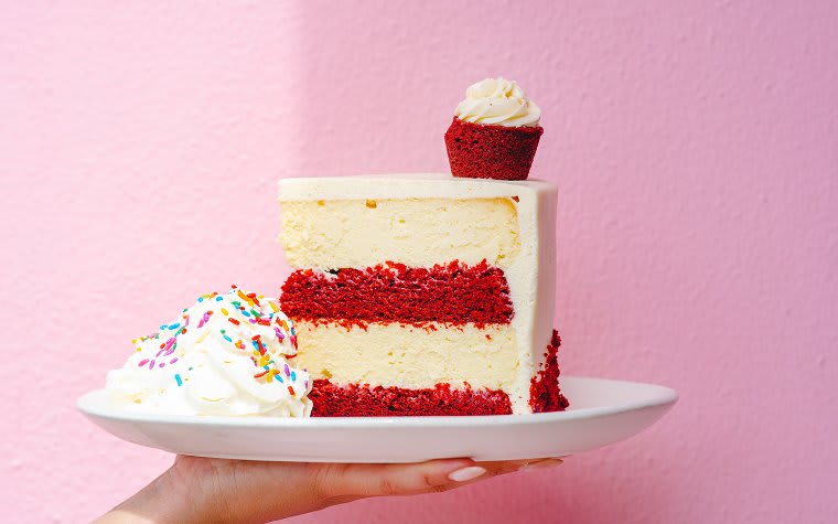 A white and red layered cake with whipped cream on a plate