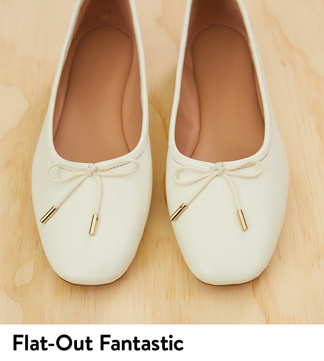 A pair of cream ballet flats with bow accents and metallic aglets.