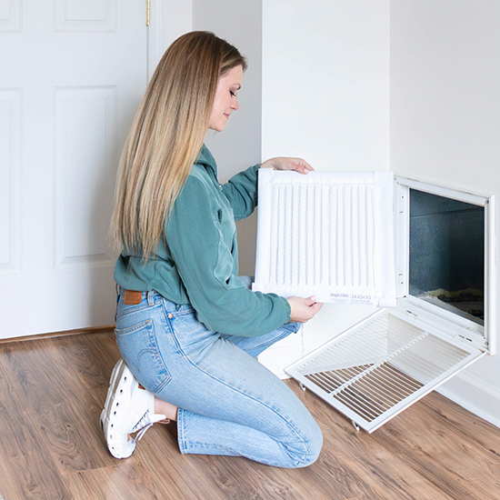 Image of woman holding air filter in front of vent