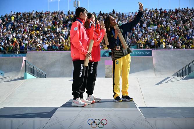 Olympic skateboarders taking selfie with Samsung phone on podium in Paris.