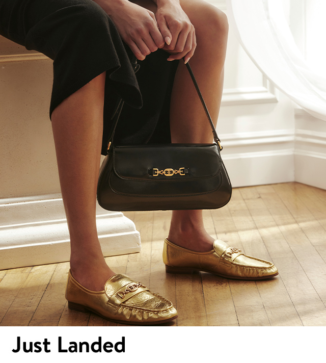 A woman holds a black handbag from Sam Edelman.