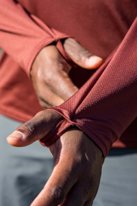 Man wearing the Mars Red Geo-T while showing off the functionality of the thumb loops