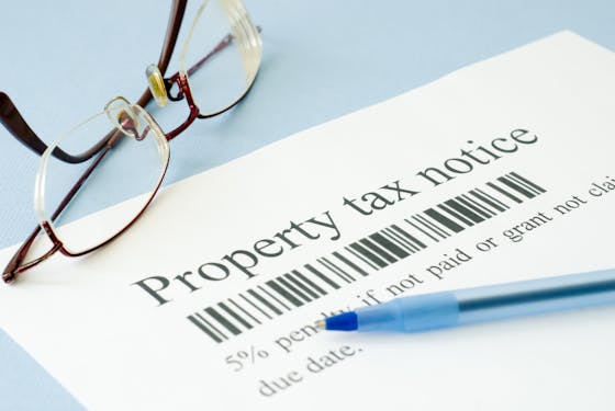 A document reading "property tax notice" sits next to glasses and a pen