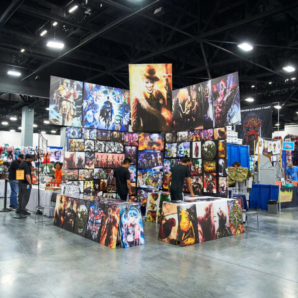 An exhibit hall show booth displays comic-themed artwork